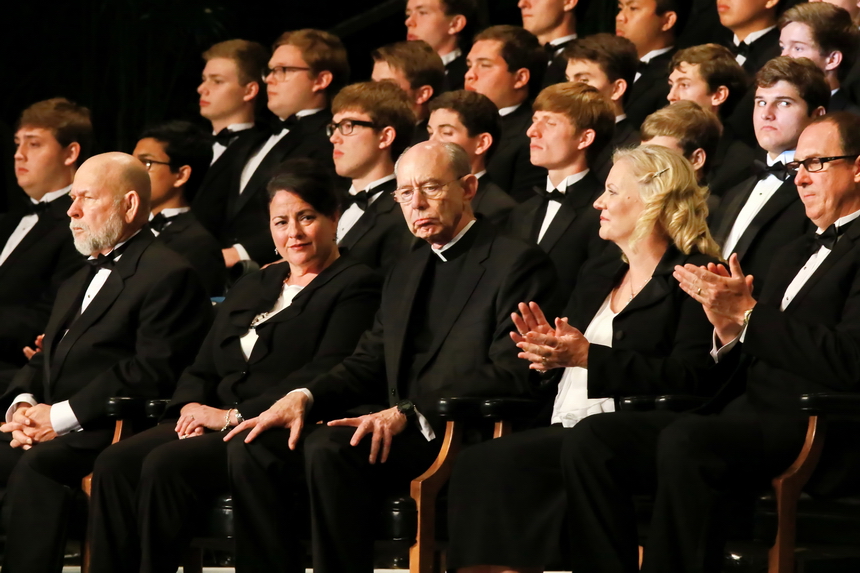 As Connor Maheu concludes his address, Fr. McGinn appears deep in thought. With Fr. McGinn on stage are Jesuit's administrators, from left, disciplinarian Mr. Top Abshire, academic assistant principal Mrs. Helen Swan, and principal Peter Kernion '90.