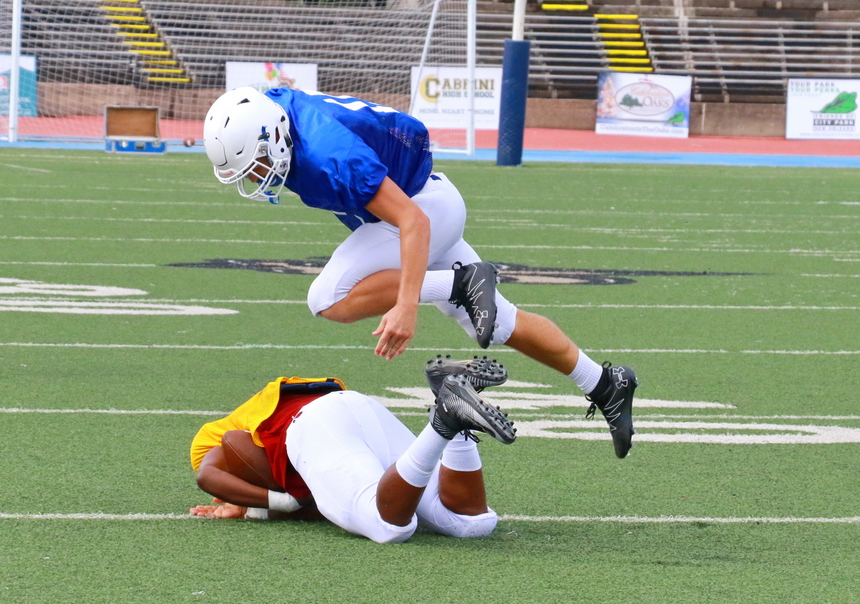 Senior defensive back Evan Loria jumps over a Roneagle receiver who almost fumbled after catching a pass during last week's scrimmage against McDonogh 35.