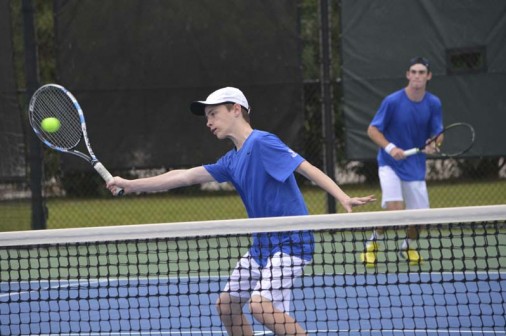 As senior Graham Buck looks on, sophomore Dex Webster poaches a volley in doubles play against St. Augustine on Tuesday, Feb. 14.